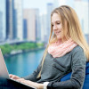 Online vs In-Person Classes Young girl using laptop study working communicating ordering online sitting in comfortable beanbag chair cityscape on the background